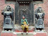 Kathmandu Bhaktapur 04-6 A Woman Sits Peacefully Between Two Statues In Taleju Chowk Just Inside The Golden Gate